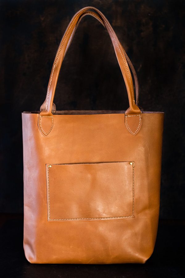 Full grain leather tote with black background.
