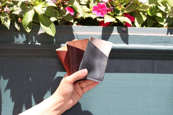 Three leather card holders against a cheery flower box.