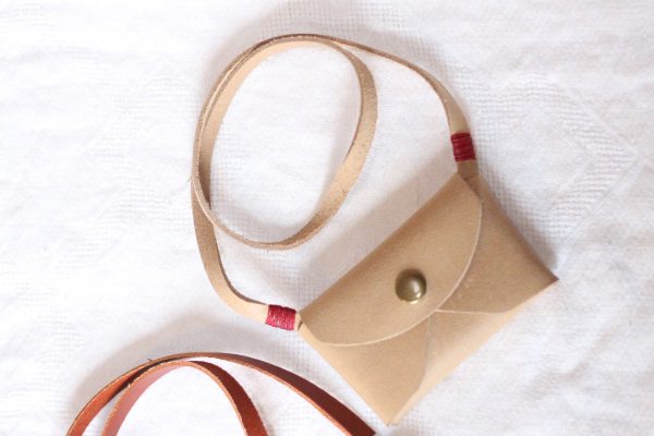 Tan kid's leather pouch purse with white background.